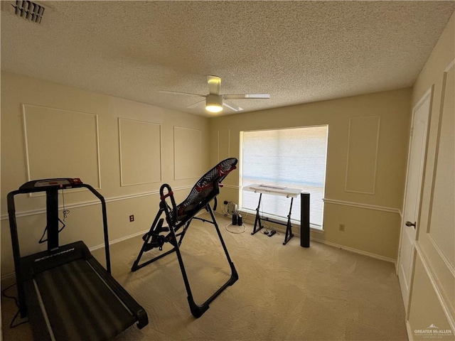 workout room with ceiling fan, light carpet, and a textured ceiling