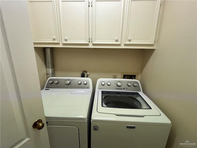 clothes washing area featuring cabinets and washer and clothes dryer