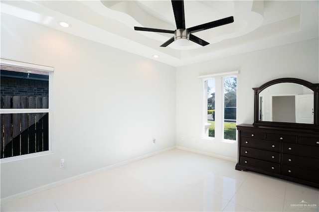 unfurnished bedroom with a tray ceiling, ceiling fan, and light tile patterned floors