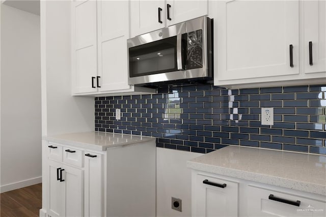 4722 Browne, Brownsville, TX 78520 - kitchen with stainless steel microwave, light stone counters, dark wood-style floors, and white cabinets