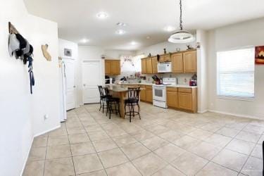 2803 Nicole Dr, Mission, TX 78574 - kitchen with a center island, white appliances, a kitchen breakfast bar, hanging light fixtures, and light tile patterned floors