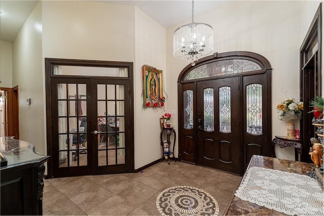 entryway with french doors, a notable chandelier, light tile patterned flooring, high vaulted ceiling, and baseboards