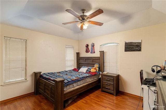 bedroom with lofted ceiling, ceiling fan, wood finished floors, and baseboards