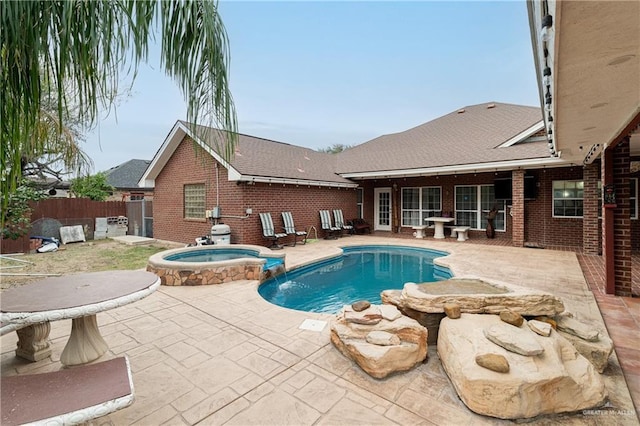 view of swimming pool featuring a patio area, fence, and a pool with connected hot tub