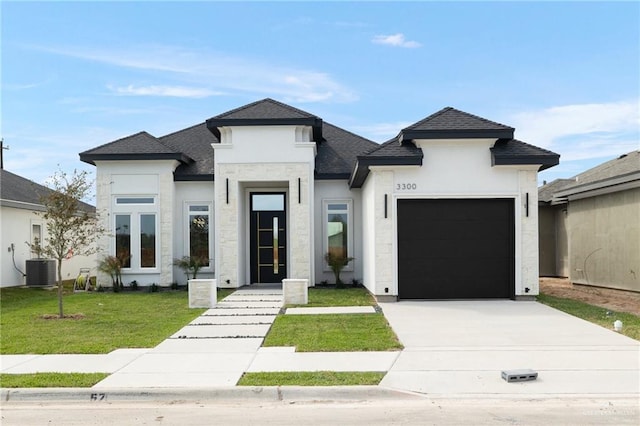 view of front of home with a garage, central air condition unit, a front lawn, and concrete driveway