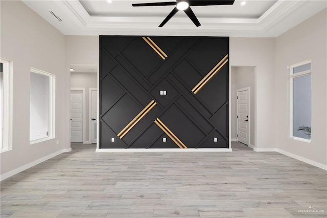 unfurnished room with light wood-style flooring, a high ceiling, baseboards, and a raised ceiling