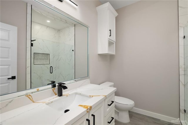 full bathroom with toilet, a marble finish shower, baseboards, and vanity