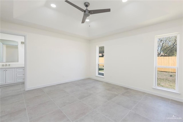 empty room with a sink, a raised ceiling, and a wealth of natural light