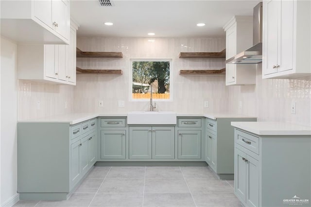 kitchen with a sink, backsplash, wall chimney range hood, and open shelves