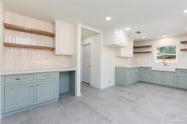 kitchen featuring decorative backsplash, open shelves, light countertops, and a sink