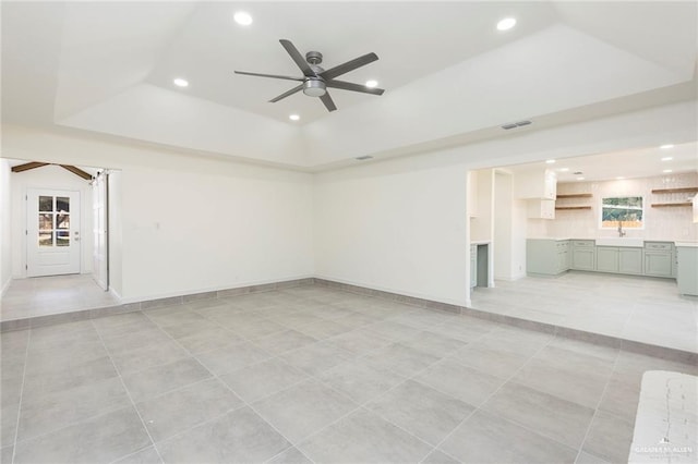 empty room featuring visible vents, ceiling fan, a tray ceiling, recessed lighting, and a sink