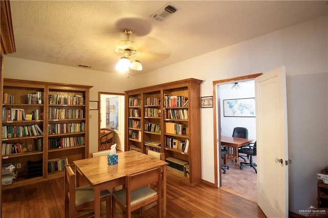 11009 Monte Cristo Rd, Edcouch, TX 78538 - sitting room with a ceiling fan, wood finished floors, an office area, bookshelves, and a textured ceiling