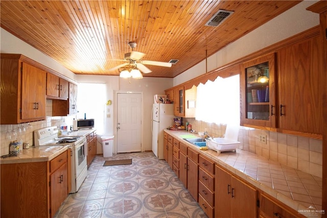 11009 Monte Cristo Rd, Edcouch, TX 78538 - kitchen featuring white appliances, tile counters, plenty of natural light, brown cabinets, and wooden ceiling