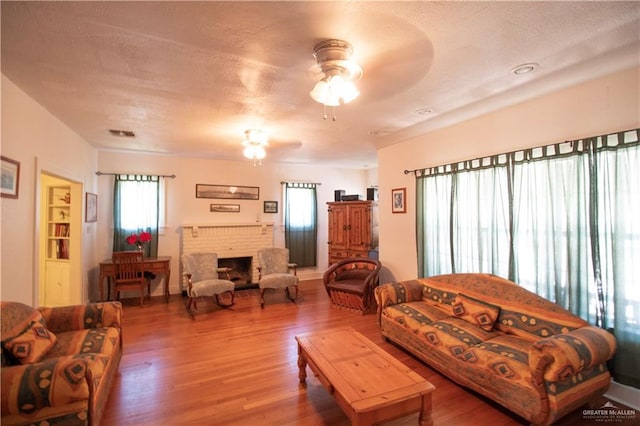 11009 Monte Cristo Rd, Edcouch, TX 78538 - living room featuring a ceiling fan, wood finished floors, a fireplace, and a textured ceiling