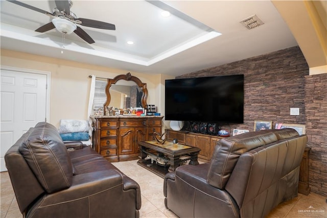 tiled living room with a raised ceiling and ceiling fan