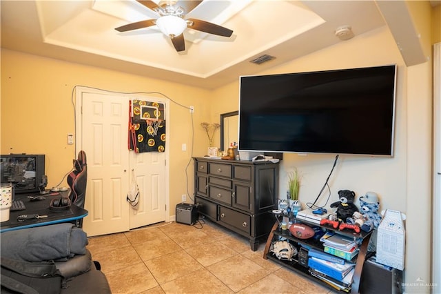 tiled living room with a raised ceiling and ceiling fan