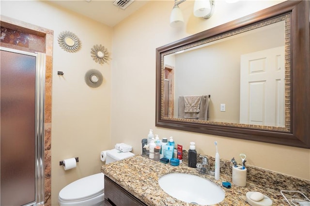 bathroom featuring vanity, toilet, and a shower with door