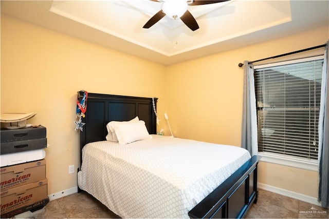 tiled bedroom featuring a raised ceiling and ceiling fan