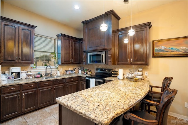 kitchen with a kitchen bar, decorative backsplash, stainless steel appliances, sink, and decorative light fixtures