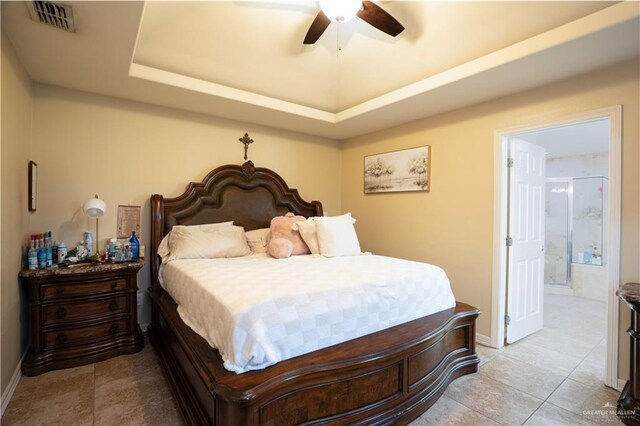 tiled bedroom with connected bathroom, a raised ceiling, and ceiling fan