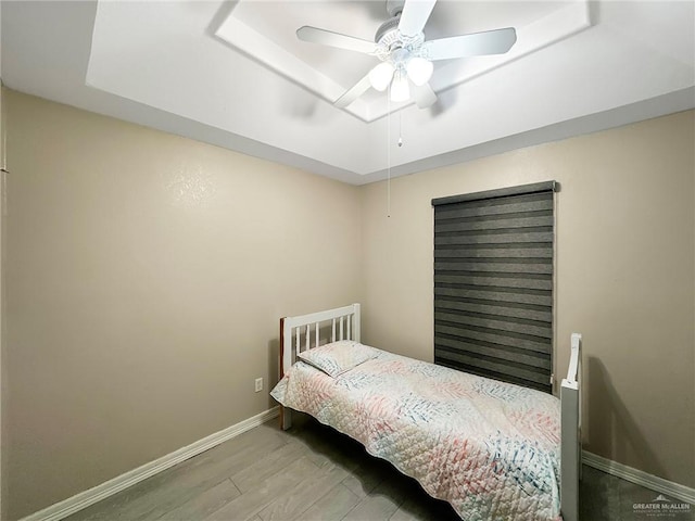 1003 Thornwood Dr, Mission, TX 78574 - bedroom featuring wood finished floors, a tray ceiling, baseboards, and ceiling fan