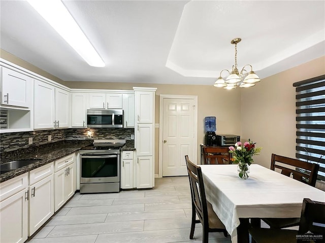 1003 Thornwood Dr, Mission, TX 78574 - kitchen with appliances with stainless steel finishes, backsplash, a sink, white cabinets, and a chandelier