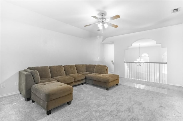 living room featuring light carpet and ceiling fan with notable chandelier