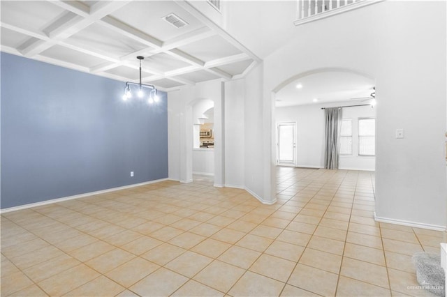 empty room featuring beam ceiling, ceiling fan, light tile patterned flooring, and coffered ceiling