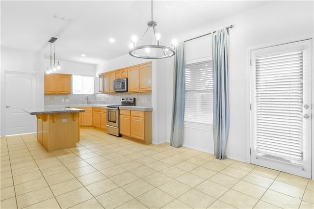 kitchen featuring stainless steel appliances, pendant lighting, a chandelier, a kitchen island, and light tile patterned flooring