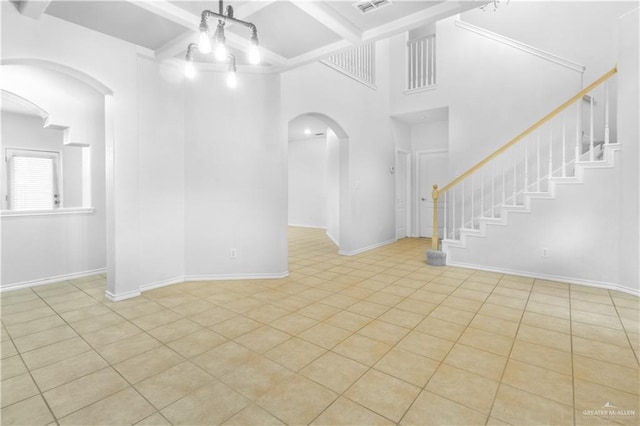 empty room with light tile patterned floors and beam ceiling