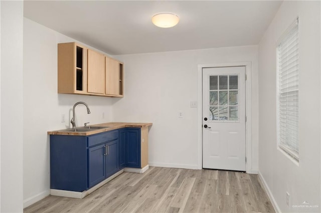 kitchen with blue cabinetry, sink, light brown cabinetry, and light hardwood / wood-style floors