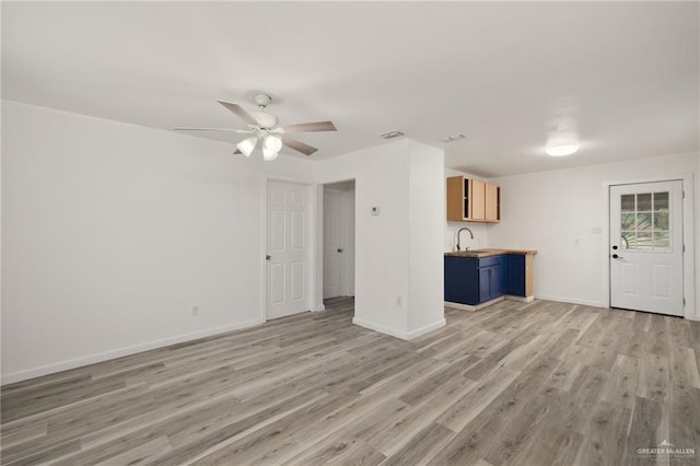 unfurnished living room featuring ceiling fan, light hardwood / wood-style floors, and sink