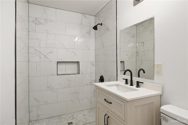 bathroom with tiled shower, vanity, and toilet