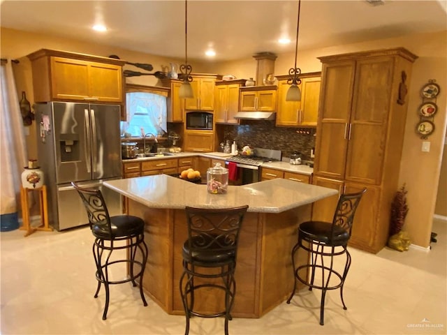 kitchen with a center island, sink, appliances with stainless steel finishes, decorative light fixtures, and a breakfast bar area