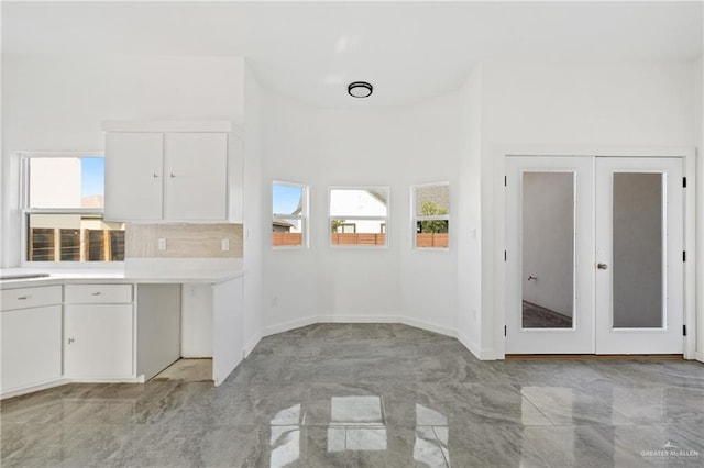 interior space with french doors, a towering ceiling, and sink