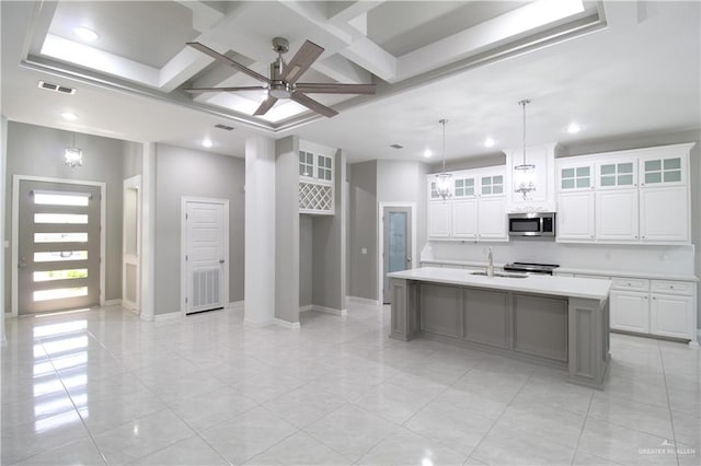 kitchen featuring beam ceiling, white cabinetry, hanging light fixtures, a center island with sink, and ceiling fan with notable chandelier