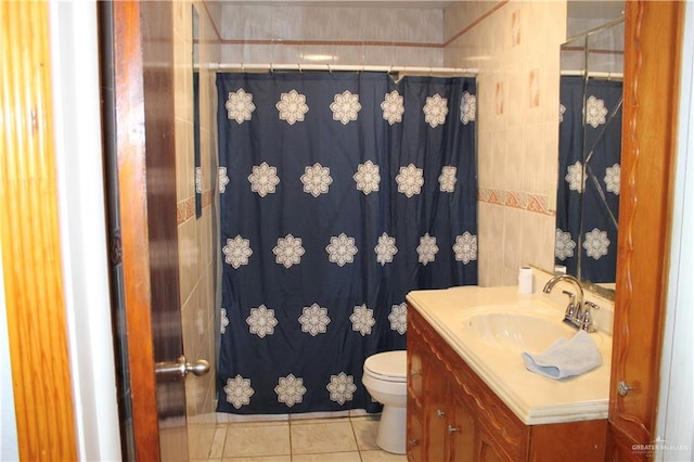 bathroom with tile patterned flooring, vanity, toilet, and tile walls