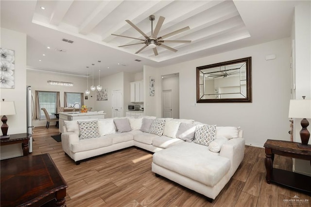 living room with a tray ceiling, ceiling fan, beamed ceiling, and hardwood / wood-style flooring