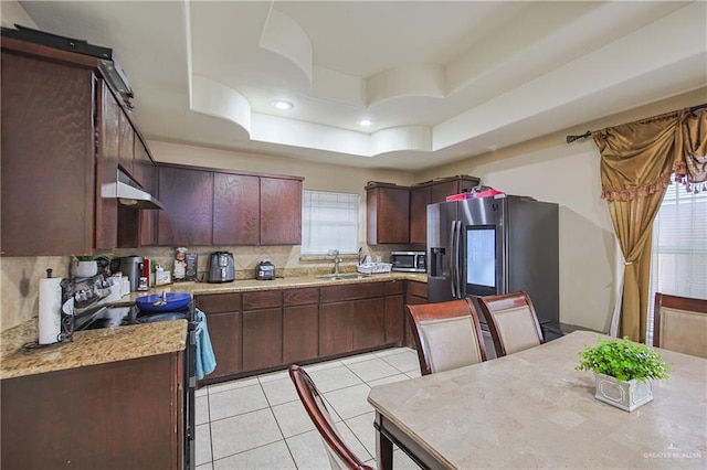 kitchen with appliances with stainless steel finishes, decorative backsplash, sink, a raised ceiling, and light tile patterned floors