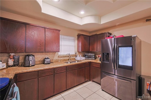 kitchen with a raised ceiling, light stone countertops, sink, and stainless steel appliances