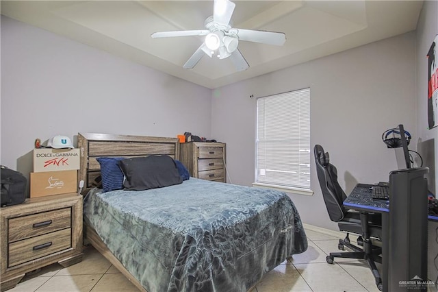 bedroom with ceiling fan, light tile patterned floors, and a tray ceiling