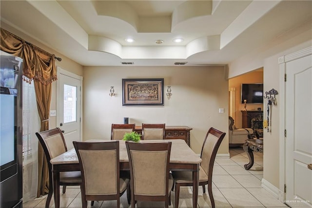 tiled dining space with a raised ceiling