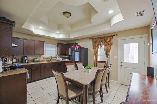 tiled dining space featuring sink and a tray ceiling