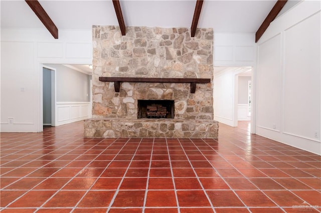 unfurnished living room featuring vaulted ceiling with beams, dark tile patterned floors, and a fireplace