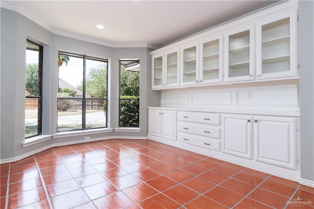 unfurnished dining area with a wealth of natural light, tile patterned flooring, and crown molding