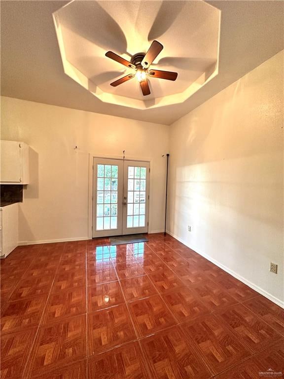 spare room featuring a tray ceiling, ceiling fan, and french doors