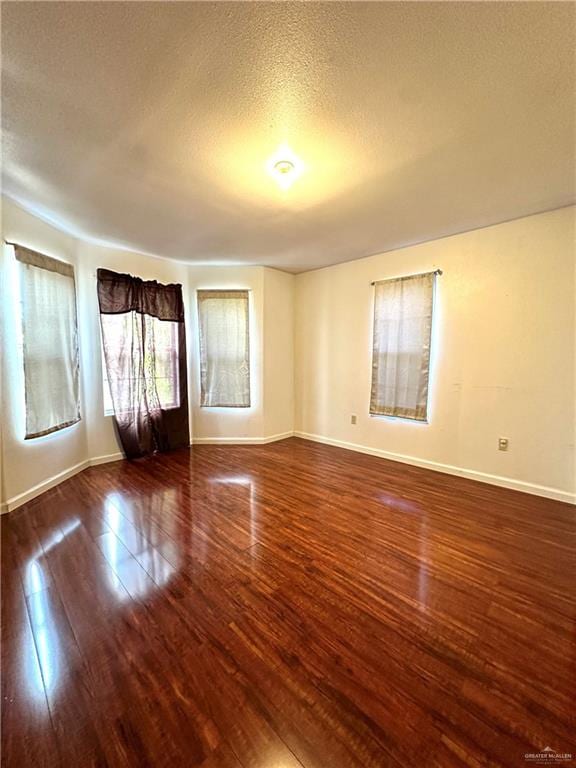 unfurnished room featuring dark hardwood / wood-style floors and a textured ceiling