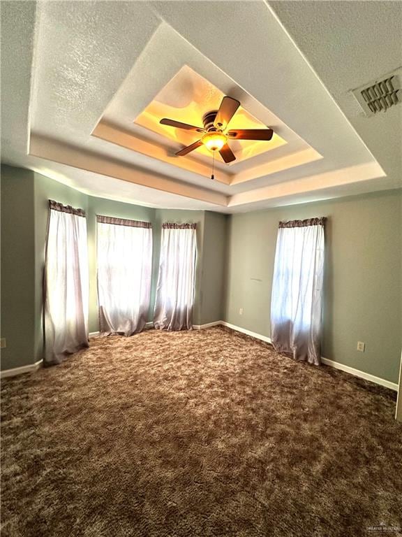 spare room featuring a tray ceiling, ceiling fan, and carpet flooring