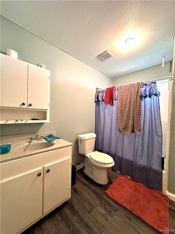 full bathroom with shower / bath combination with curtain, vanity, a textured ceiling, hardwood / wood-style floors, and toilet