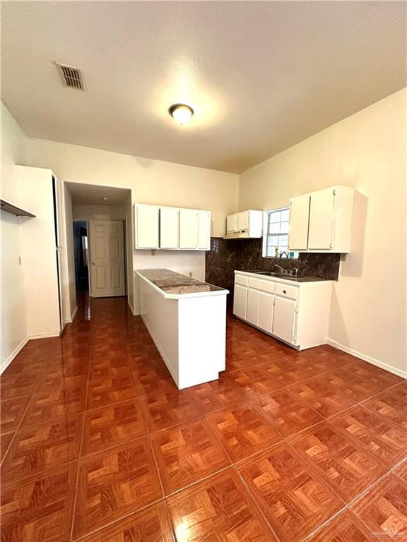 kitchen featuring decorative backsplash, white cabinetry, and sink